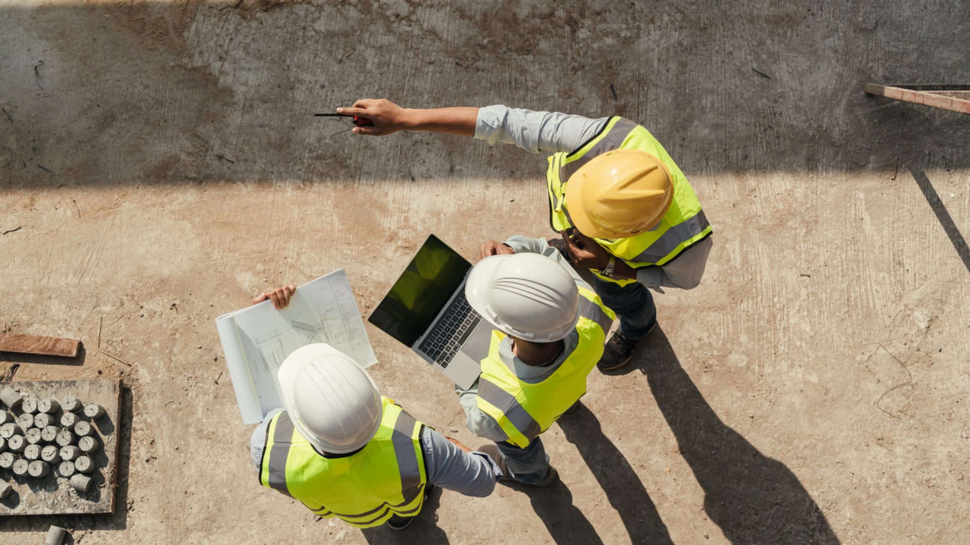 Commercial Management in Construction shown by construction workers in hard hats reviewing paperwork on site